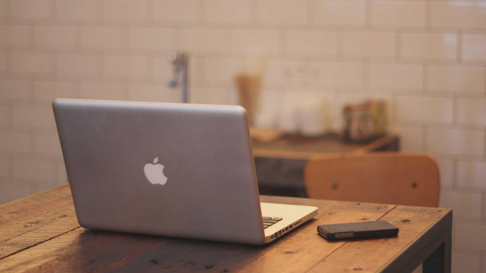 Laptop, photo ID and phone on a cream desk